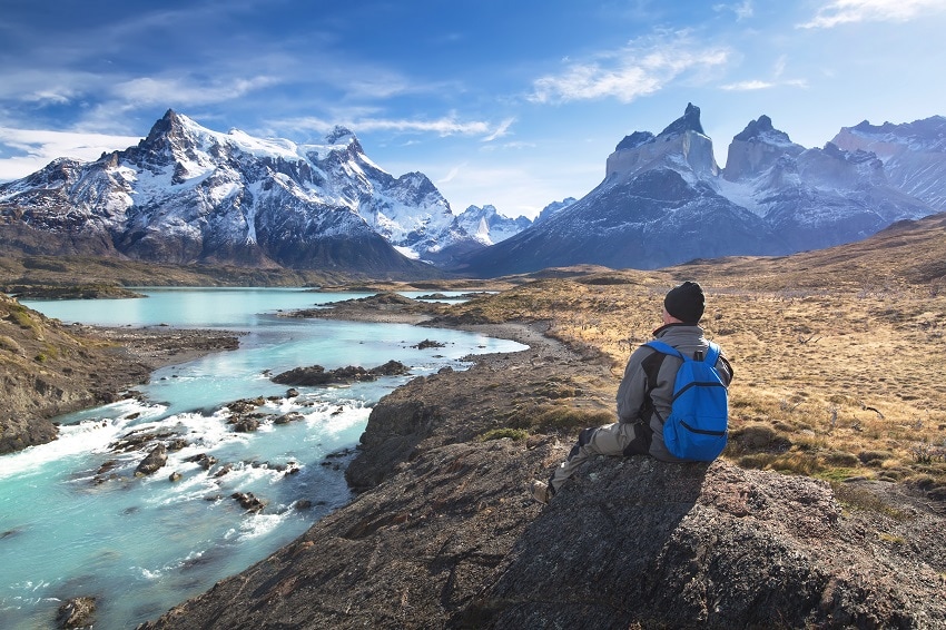 hiker sat on a rock looking at Torres del Paine National Park
