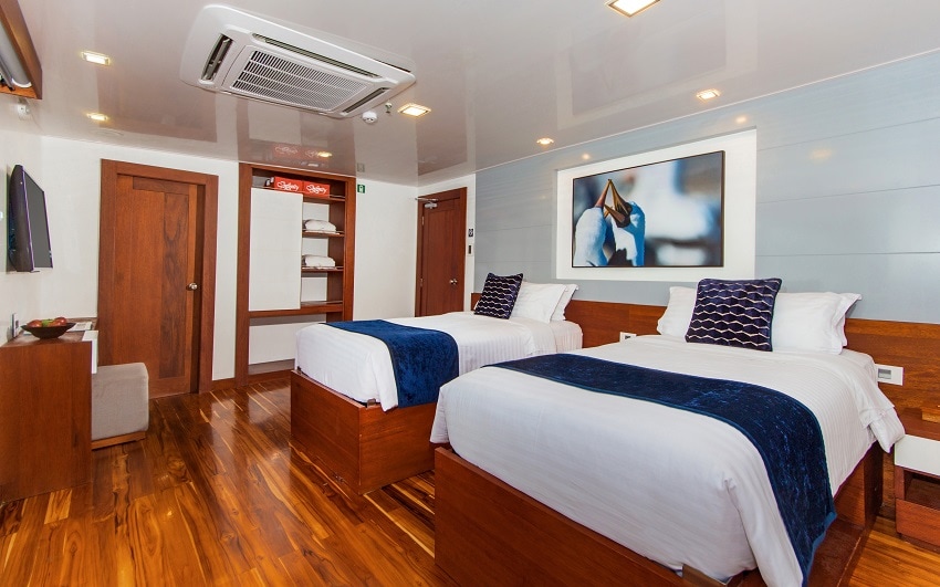 Cabin aboard the infinity Yacht Galapagos, Double Bed, with white and blue sheeting and wooden flooring