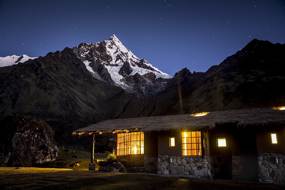 Mountain Lodge at nighttime on a starry night with a snowcapped mountain in the background