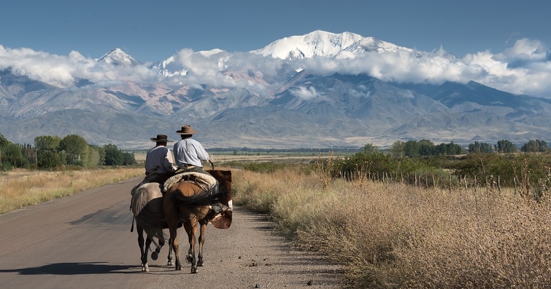 Horseback riders on a route with a view of Mendoza Mountain in background
