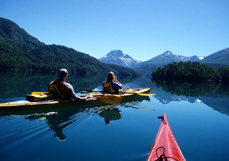 couple on kayak on lake in Bariloche with mountains in the rear
