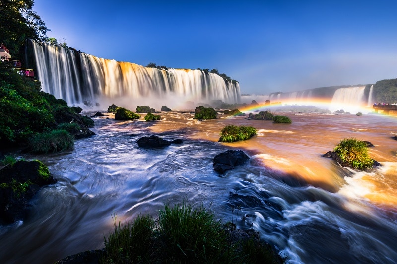 Iguazu Falls at sunset with a low level rainbow over the river